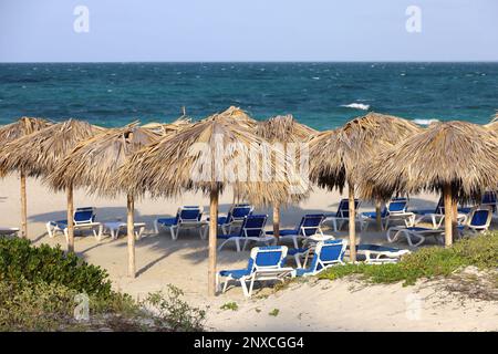 Leerer Sandstrand mit Korbschirmen und Liegestühlen. Malerischer Blick auf das blaue Meer mit Wellen Stockfoto