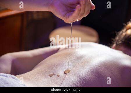 Goiania, Goias, Brasilien – 01. Oktober 2022: Detail eines Therapeuten, der Öl auf den Rücken eines Patienten gießt, der auf einer Trage liegt. Stockfoto