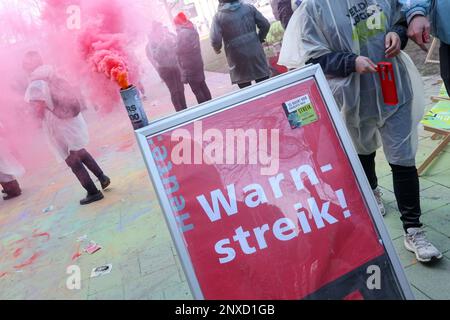 Hamburg, Deutschland. 01. März 2023. Teilnehmer eines landesweiten Jugendstreiks von Praktikanten und Doppelschülern im öffentlichen Sektor demonstrieren vor dem Gewerkschaftsgebäude. Ein roter Bengalo brennt auf einem Schild mit der Aufschrift „WARNING Strike“. In der aktuellen Runde der Tarifverhandlungen fordert Verdi eine Erhöhung der Lehrstellen- und Studentengehälter um 200 Euro pro Monat. Kredit: Bodo Marks/Bodo Marks/dpa/Alamy Live News Stockfoto