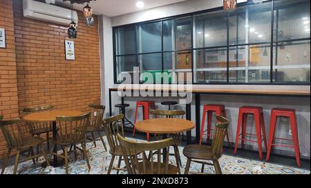 Café-Atmosphäre vor der Eröffnung, Holztische mit Holzstühlen und rote Hochstühle Stockfoto