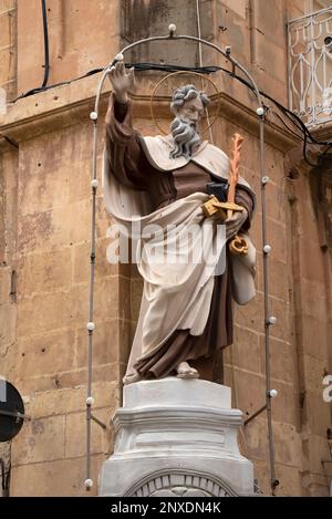 Valletta, Malta - 12. November 2022: Restaurierte und bemalte Statue eines Heiligen mit Schlüsseln und Flammenschwert in der Nische eines Kalksteinhauses Stockfoto