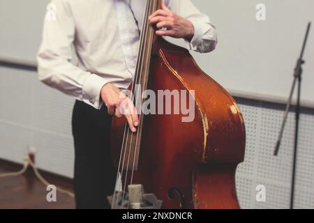 Kontrastierender Cellist-Spieler in Kopfhörern während der Probe, Aufnahme von Ton für ein neues Album-Lied im Studio, Cello-Violoncellist-Musiker mit Mikrofon A. Stockfoto