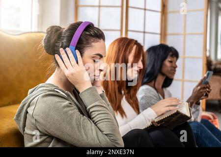 Multikulturelle weibliche Freundinnen, die Spaß haben, einzeln verschiedene Dinge zu tun - Konzept der Unkommunikation zwischen Menschen, zusammen, aber geteilt durch Dif Stockfoto