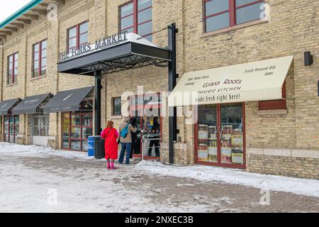 Drei Personen gehen im Winter in den Eingang zum Forks Market in Winnipeg, Manitoba, Kanada. Stockfoto