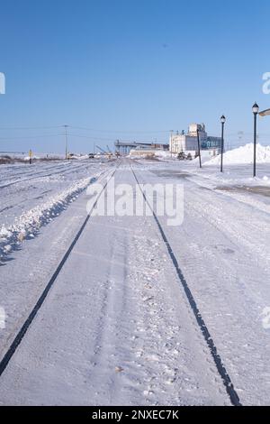 Schneebedeckte Bahngleise hinter dem Bahnhof in Churchill, Manitoba, Kanada im Winter mit dem Churchill Grain Elevator Terminal im d Stockfoto