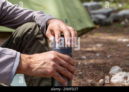 Der Mann stellt Thermosflaschen auf einen Baumstumpf Stockfoto