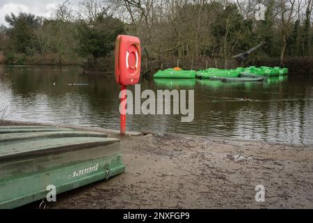 Neuere Tretboote sind am 22. Februar 2023 in Dulwich Park, Southwark, in London, England, auf der anderen Seite des Sees von einem Rettungsboot und einem älteren Boot aus zu sehen. Stockfoto