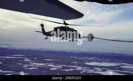 Alaska Air National Guardsmen mit der 210. Rettungsstaffel fliegen einen HH-60G Pave Hawk Helikopter während eines Air-to-Air-Tankvorgangs aus einem 211. RQS HC-130J Combat King II Flugzeug über dem Lower Susitna Valley bei Anchorage, Alaska, 7. Februar 2023. Beide Flugzeuge und das Rettungspersonal der 212. RQS sind für die Such- und Rettungsmission des Bundes in der riesigen arktischen Region Alaska alarmiert. Die Luftbetankungskapazität des HC-130F erweitert das Angebot des HH-60G Pave Hawk für Such- und Bergungsmissionen erheblich. Stockfoto