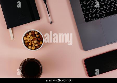Der Kaffee liegt auf dem Tisch neben dem Telefon und dem Laptop. Modell Stockfoto