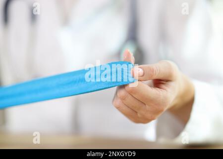 Physiotherapeutin mit blauem Klebeband in den Händen Stockfoto