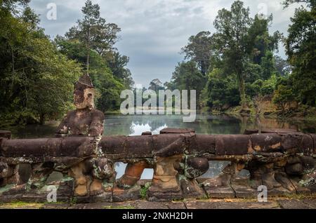 Eine geschnitzte Steinfigur, die einen Nagakörper hält, um eine Balustrade über einem Wassergraben am Eingang zum Preah Khan Tempel in Angkor nahe Siem Reap, Kambodscha, zu bilden. Stockfoto