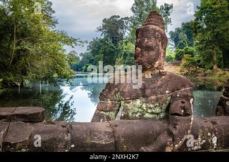 Eine geschnitzte Steinfigur, die einen Nagakörper hält, um eine Balustrade über einem Wassergraben am Eingang zum Preah Khan Tempel in Angkor nahe Siem Reap, Kambodscha, zu bilden. Stockfoto