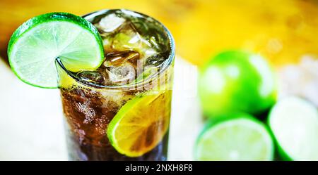 Cuba Libre Cocktail mit Kalk, Eis, Minze und Fach auf hölzernen Tisch Stockfoto