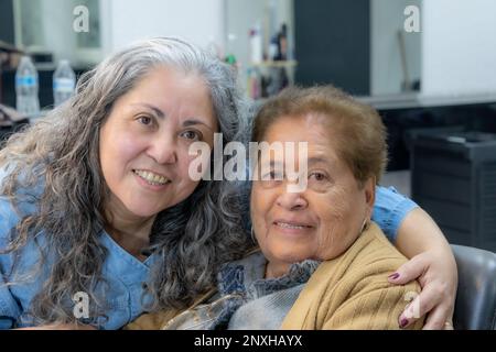 Zwei lateinamerikanische Frauen, Mutter und Tochter, die lächeln und glücklich sind, in die Kamera schauen, kein Make-up, lässige Kleidung Stockfoto