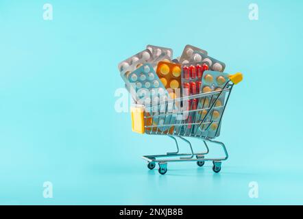 Einkaufswagen mit Pillen und Medizin auf blauem Hintergrund. Stockfoto