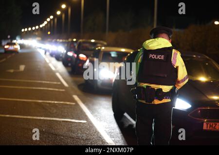 Polizeibeamte, die Autofahrer-Details in der Nähe des Sportkomplexes in der Gegend der Killyclogher Road von Omagh, Co Tyrone, untersuchen, eine Woche später, als der außerdienstliche PSNI Detective Chief Inspector John Caldwell mehrmals von maskierten Männern vor jungen Leuten erschossen wurde, die er trainiert hatte. Herr Caldwell befindet sich nach dem Anschlag am vergangenen Mittwochabend im Krankenhaus in einem kritischen, aber stabilen Zustand. Die Polizei von Nordirland (PSNI) glaubt, dass der Anschlag mit dem Terror zusammenhängt, und beschreibt die Neue IRA als ihre Hauptuntersuchungslinie. Bilddatum: Mittwoch, 1. März 2023. Stockfoto