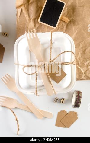 Geschlossene Bento-Kuchenbox mit einem Holzlöffel Band. Geschenkbox mit leckerem Bento. Kuchenverpackung. Lieferung. Selbstgebackene Idee für den Urlaub. Klein Stockfoto