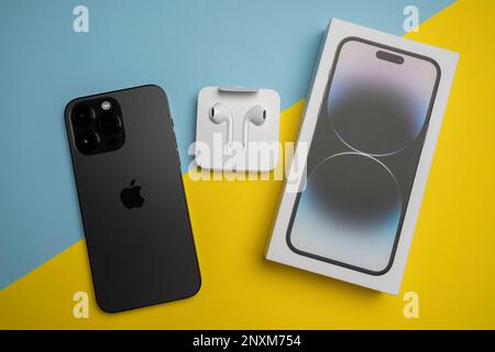 Neue iPhone 14 pro max und Apple Ohrhörer, AirPods weiße Ohrhörer in einer offenen Box. Isolierter, farbenfroher Hintergrund. Stockfoto
