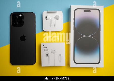 Neue iPhone 14 pro max und Apple Ohrhörer, AirPods weiße Ohrhörer in einer offenen Box. Isolierter, farbenfroher Hintergrund. Stockfoto