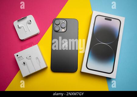 Neue iPhone 14 pro max und Apple Ohrhörer, AirPods weiße Ohrhörer in einer offenen Box. Isolierter, farbenfroher Hintergrund. Stockfoto