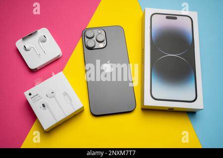 Neue iPhone 14 pro max und Apple Ohrhörer, AirPods weiße Ohrhörer in einer offenen Box. Isolierter, farbenfroher Hintergrund. Stockfoto