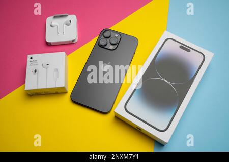 Neue iPhone 14 pro max und Apple Ohrhörer, AirPods weiße Ohrhörer in einer offenen Box. Isolierter, farbenfroher Hintergrund. Stockfoto