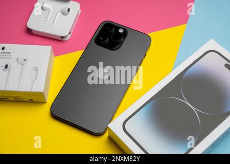 Neue iPhone 14 pro max und Apple Ohrhörer, AirPods weiße Ohrhörer in einer offenen Box. Isolierter, farbenfroher Hintergrund. Stockfoto
