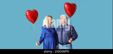 Glückliches, reifes Paar mit herzförmigen Ballons auf blauem Hintergrund Stockfoto