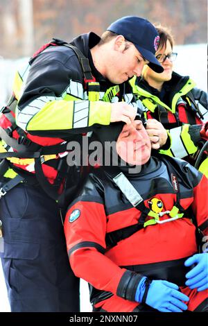 Feuerwehrleute mit dem Tauchteam der Feuerwehr üben ein Eisrettungsszenario am 11. Januar 2023 an einem gefrorenen Big Sandy Lake auf der South Post in Fort McCoy, Wisconsin. Mehrere Feuerwehrleute aus dem Team zogen einen Anzug an, schnallten sich einen Lufttank und eine Vollmaske an und tauchten in die Tiefen des Big Sandy Lake unter dem Eis an der South Post von Fort McCoy. Die Taucher bearbeiteten Tiefen von bis zu 15 Fuß oder mehr, um verschiedene Arten von Rettungsszenarien unter der Anleitung von anderen Feuerwehrleuten durchzuführen. Taucher wechselten sich ab und gingen in und aus dem gleichen Loch, das ich geschnitten hatte Stockfoto