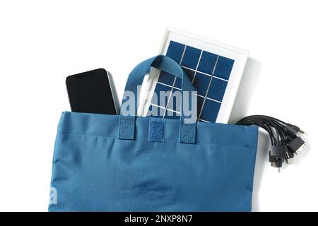 Tasche mit tragbarem Solarpanel, Kabeln und Mobiltelefon auf weißem Hintergrund Stockfoto