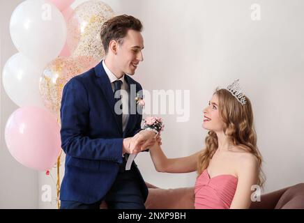 Ein Teenager, der sich beim Abschlussball Ansteckblume um das Handgelenk seiner Freundin bindet Stockfoto