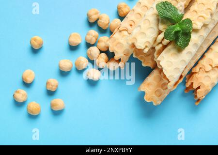 Köstliche Waffeln, Haselnüsse und Minze auf blauem Hintergrund Stockfoto