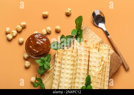 Gehen Sie an Bord mit köstlichen Waffeln, gekochter Kondensmilch, Minze und Haselnüssen auf orangefarbenem Hintergrund Stockfoto