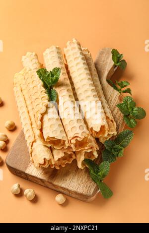 Gehen Sie an Bord mit köstlichen Waffeln, Minze und Haselnüssen auf orangefarbenem Hintergrund Stockfoto