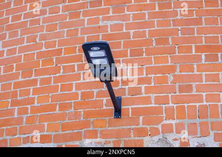 Laterne auf dem Hintergrund der alten Backsteinmauer. Eine Lampe auf einem alten Ziegelstein. Straßenbeleuchtung. Modernes LED-Licht. Stockfoto