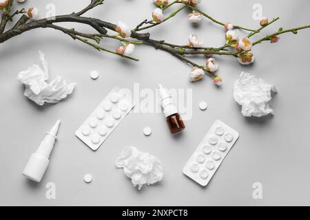 Nasentropfen mit Pillen, Blumen und Taschentüchern auf grauem Hintergrund. Saisonales Allergiekonzept Stockfoto