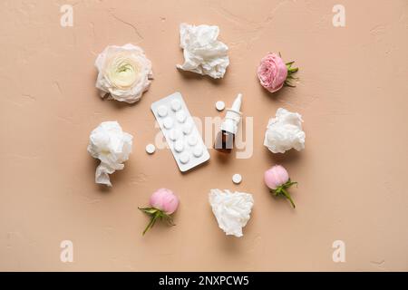 Nasentropfen mit Pillen, Blumen und Taschentüchern auf beigefarbenem Hintergrund. Saisonales Allergiekonzept Stockfoto