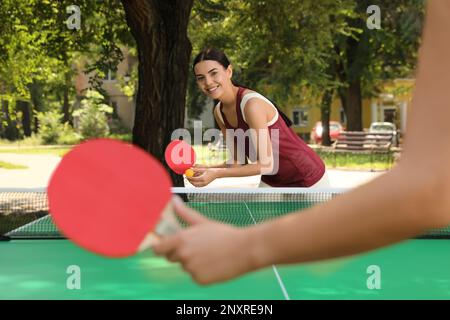 Junge Frauen spielen Tischtennis im Park Stockfoto