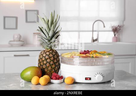 Obst und Trockner auf grauem Marmortisch in der Küche Stockfoto