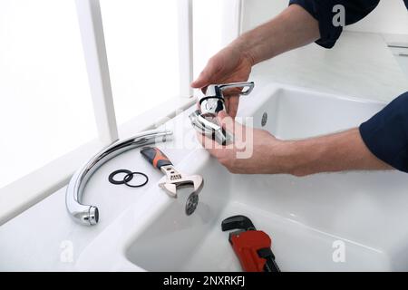 Professioneller Klempner repariert Wasserhahn in der Küche, Nahaufnahme Stockfoto