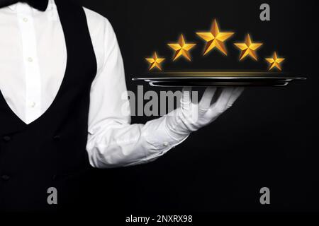 5-Sterne-Luxushotel. Kellner mit Tablett auf schwarzem Hintergrund, Schließung Stockfoto