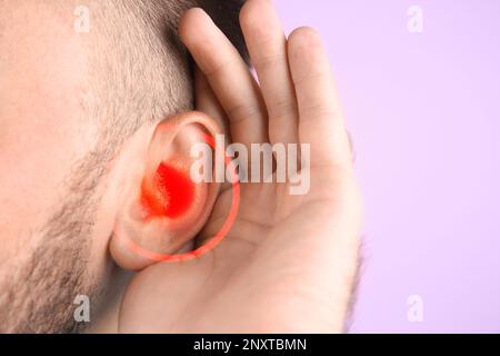 Mann mit Ohrenschmerzen auf rosa Hintergrund, Nahaufnahme Stockfoto