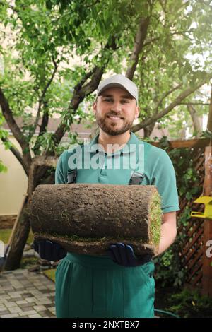 Junger Arbeiter, der gerollte Grassoße im Garten hält Stockfoto