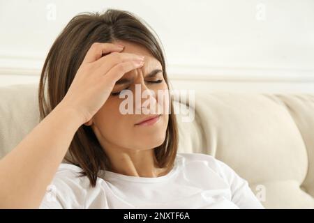 Junge Frau mit Migräne auf dem Sofa zu Hause Stockfoto