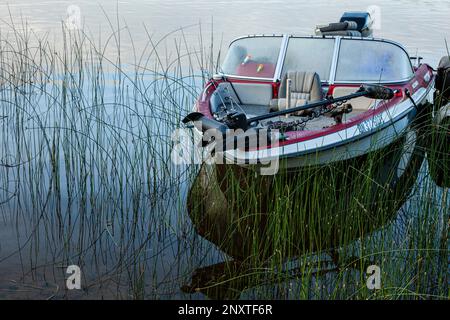 Stockfoto eines alten Glasfaser-Motorboots, das am frühen Morgen mit Angelausrüstung an einer Anlegestelle festgebunden ist. Angeln in Ontario. Stockfoto