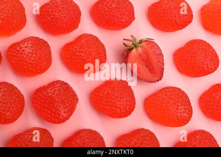 Leckere Gummibonbons und frische Erdbeeren auf pinkfarbenem Hintergrund, flach liegend Stockfoto