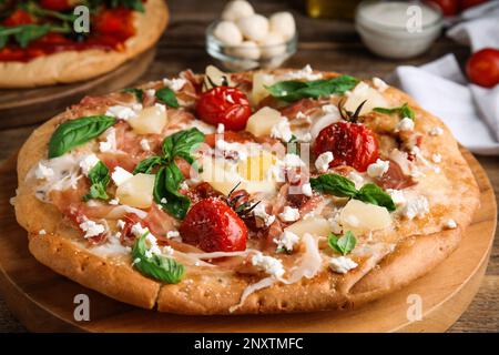 Pita Pizza mit Prosciutto, Ananas, gegrillten Tomaten und Ei auf Holztablett, Nahaufnahme Stockfoto
