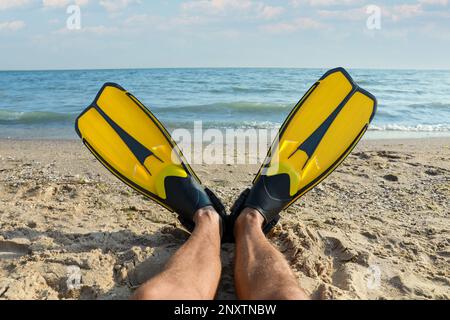 Ein Mann in Flossen nahe dem Meer am Strand, Nahaufnahme Stockfoto