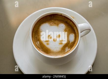 Form einer Katze oder eines Katzengesichts, das in den Milchschaum gezogen wird, oder Schaum auf einer Tasse Kaffee Stockfoto