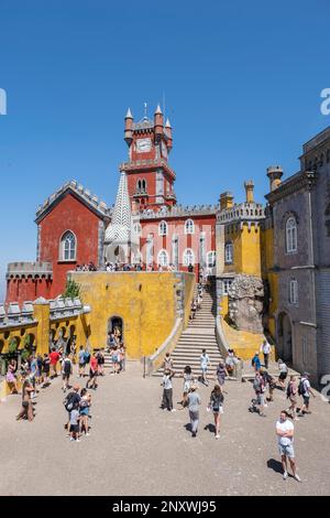 Innenhof des bunten Pena-Palastes in Sintra, Portugal mit seinen roten Türmen, Touristen besuchen das Gebäude an einem Sommertag, vertikal Stockfoto